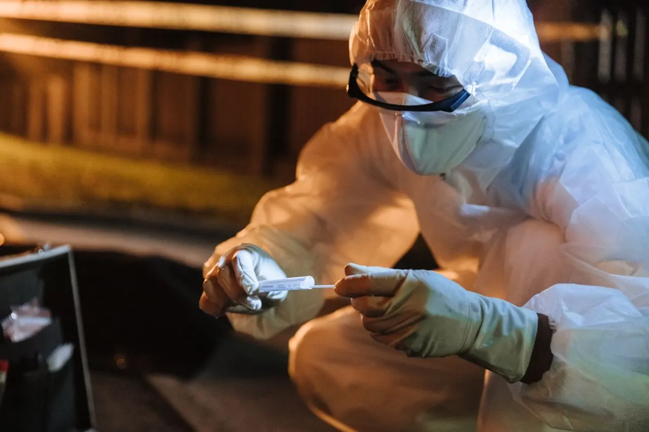A forensic technician seals a swab into a paper evidence packet behind cordon tape at night, the hands-on training offered by California's forensic science colleges and degree programs