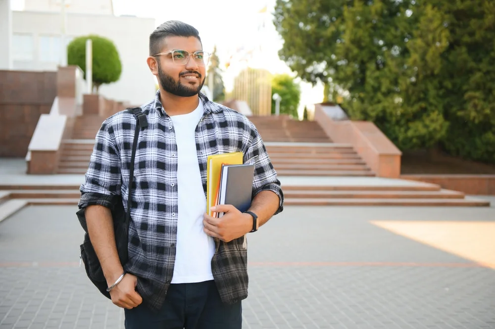 Student carrying books on campus steps outdoors