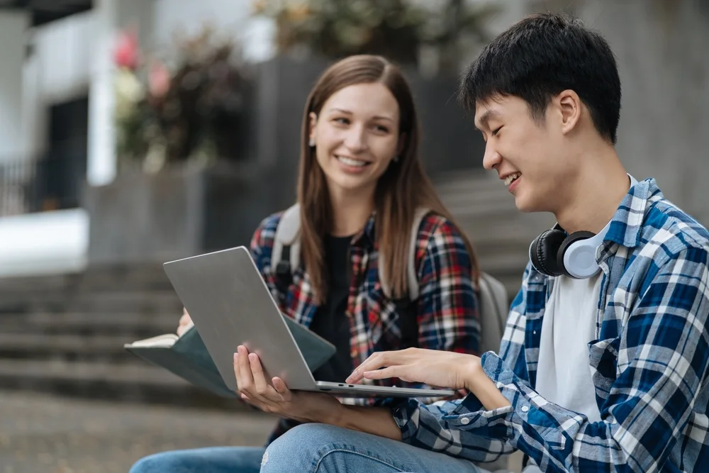 Two students looking at a laptop on outdoor steps
