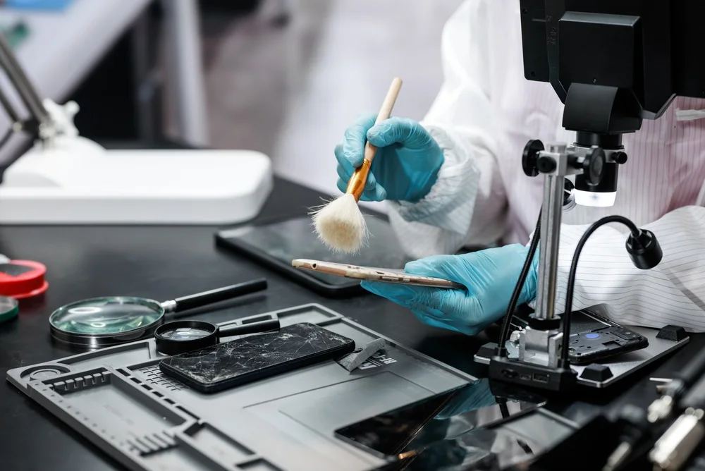 Technician brushing powder onto a device beneath a copy stand camera