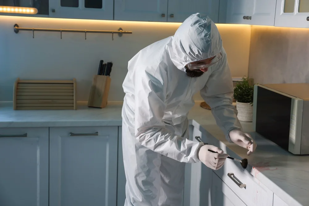 Investigator dusting a drawer handle for fingerprints