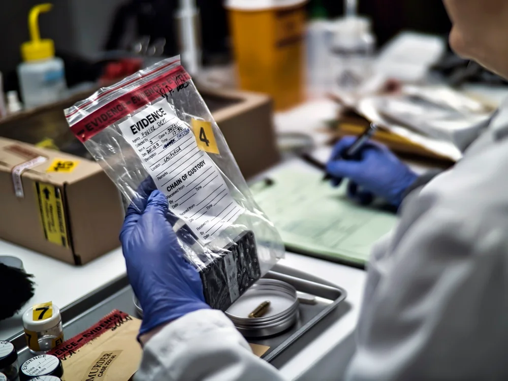 Technician holding a sealed evidence bag containing an item