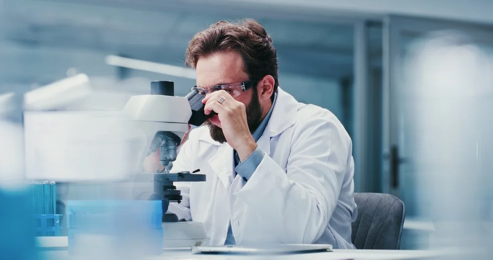 Scientist examining a sample through a microscope