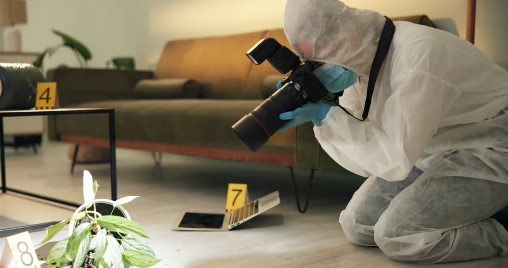 Investigator photographing numbered evidence inside a room