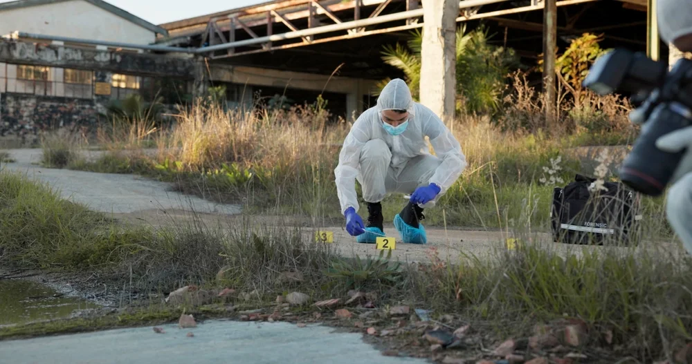 Investigator photographing markers at a wide outdoor scene
