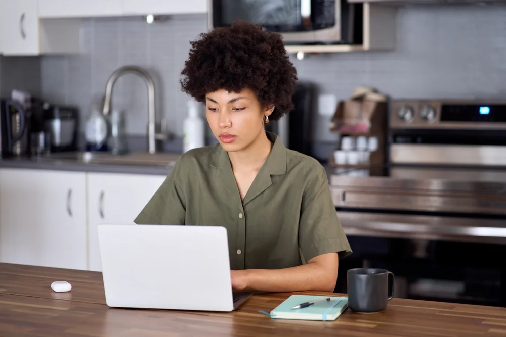 Student working on a laptop at a kitchen counter
