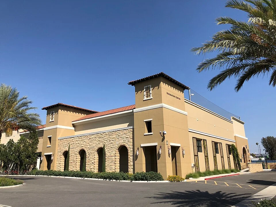 A Spanish-style academic building with arched windows and palm trees at California Baptist University in Riverside