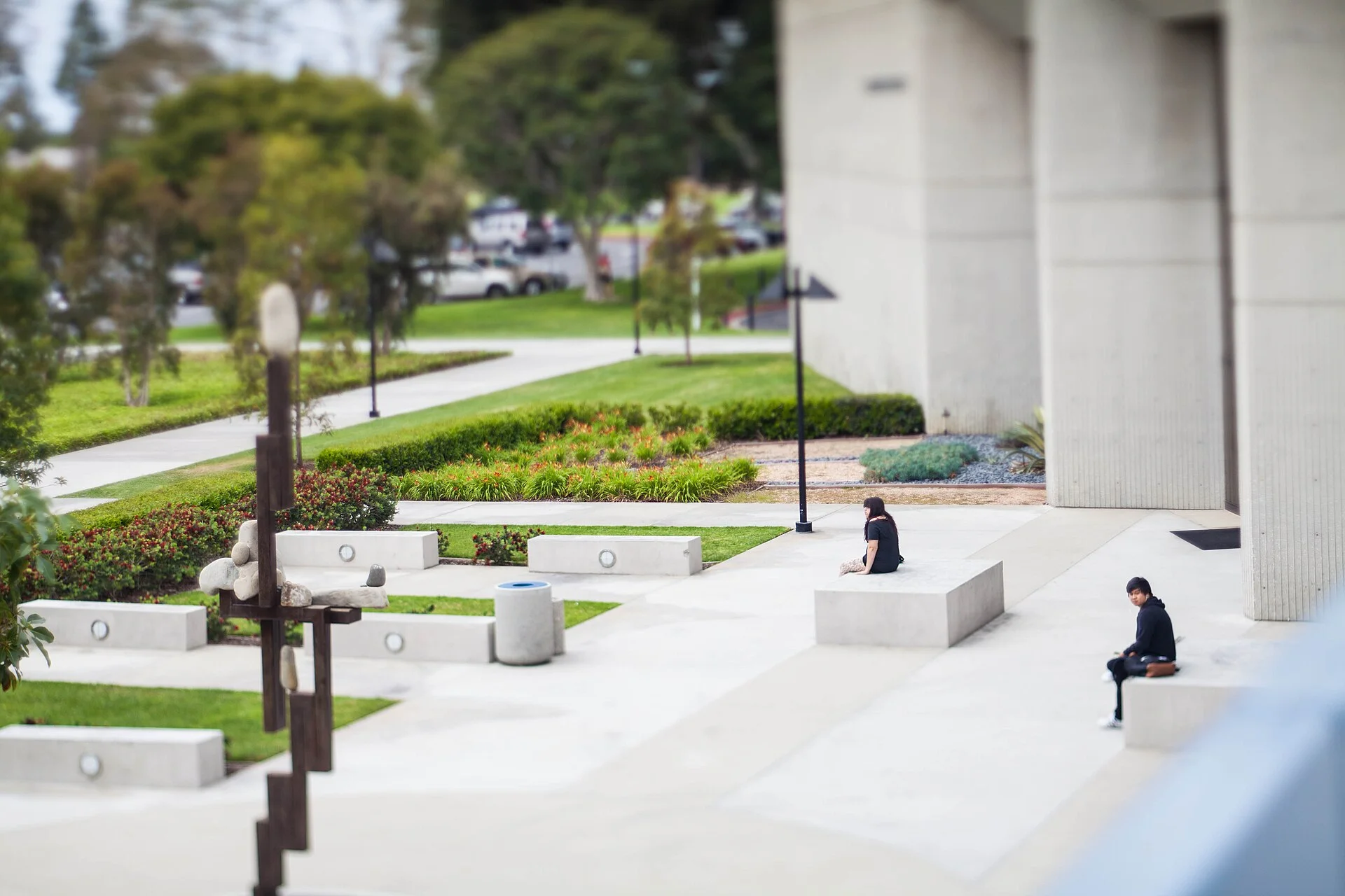 A paved campus plaza at Cypress College with concrete columns, lamp posts and planted beds