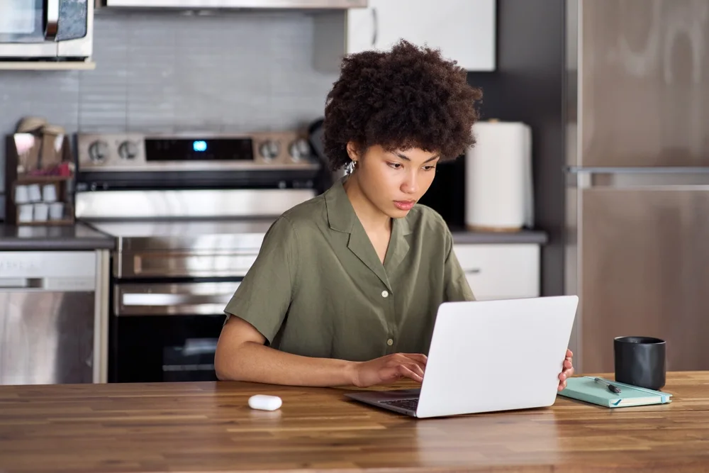 Student studying on a laptop at a kitchen counter