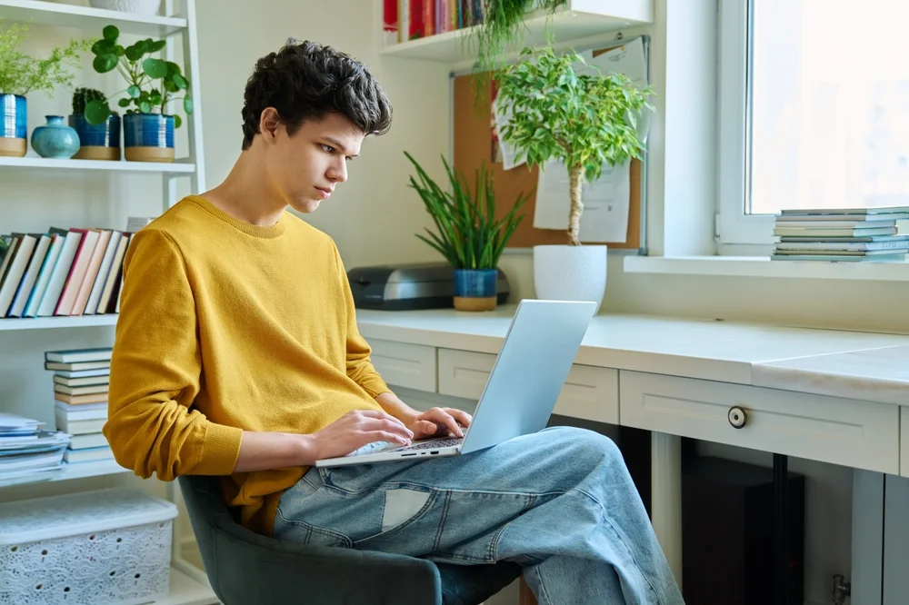 Student using a laptop by a window