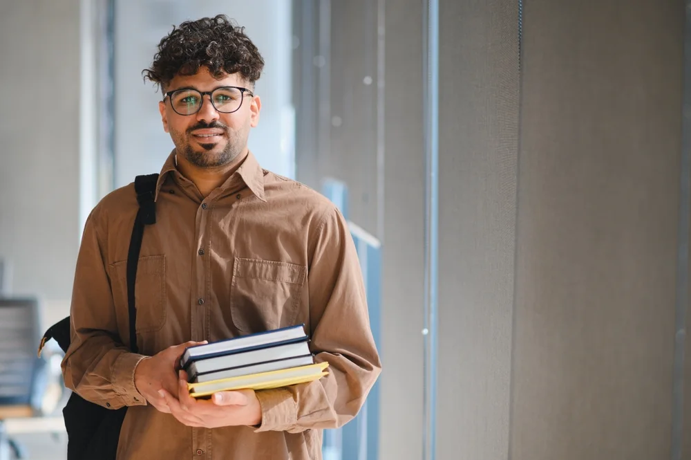 Student carrying textbooks in a campus corridor