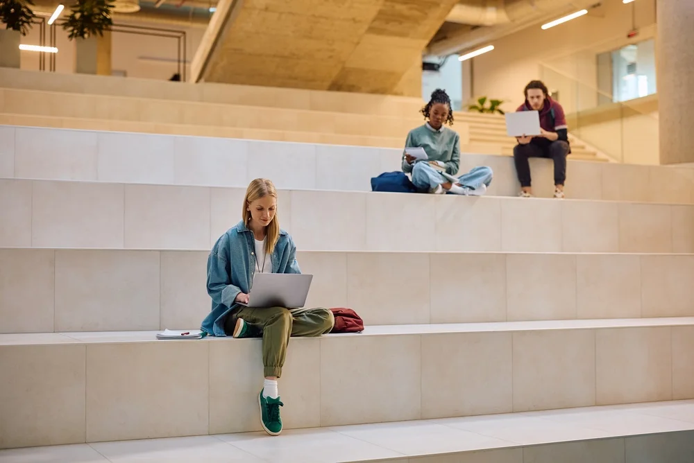 Students working on laptops on interior steps