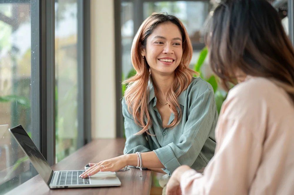 Two students talking over a laptop